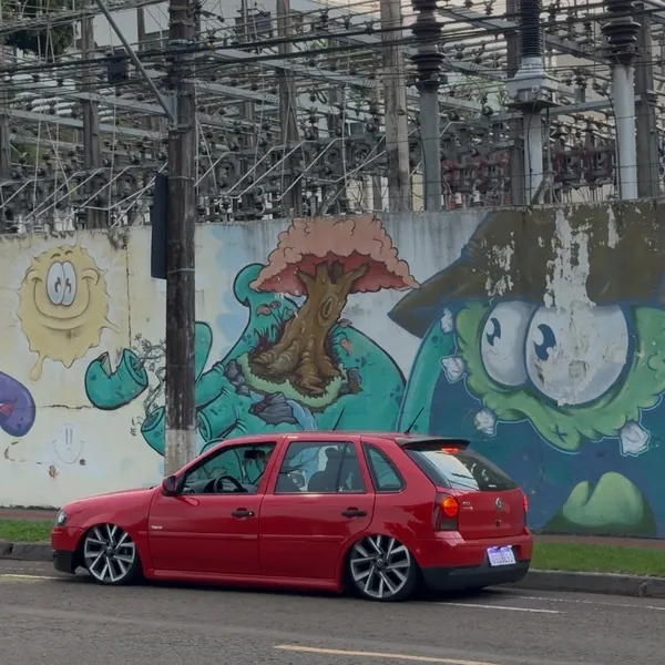 Gol G4 vermelho rebaixado diante de um muro grafitado