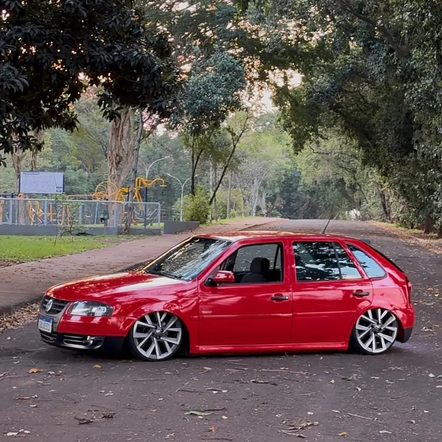 Gol G4 vermelho rebaixado, com rodas aro 18, parado numa rua arborizada
